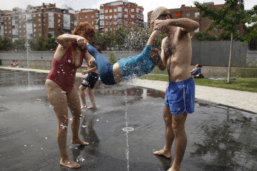 epa10009338 A family refresh themselves at a public fountain in Madrid, Spain, 12 June 2022. The heat continues to hit much of Spain, a situation that, according to all forecasts, will continue for se ...