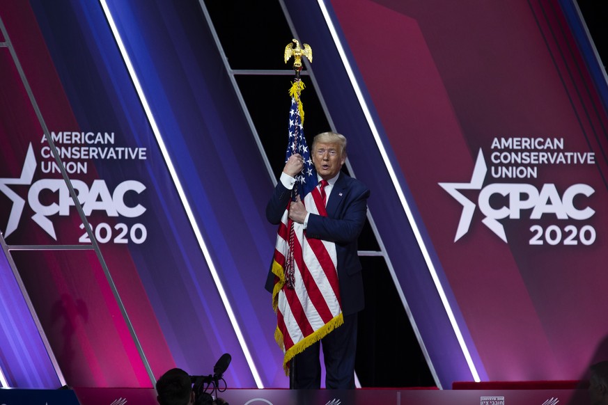 FILE - In this Feb. 29, 2020 file photo, President Donald Trump hugs and kisses the American flag after speaking at Conservative Political Action Conference, CPAC 2020, at the National Harbor, in Oxon ...