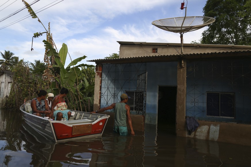 Luzia Barbosa de Oliveira, in white, accompanied by family members, is transported on a boat to her home partially submerged by flood waters in Sambaituba, a rural area of Ilheus, Bahia state, Brazil, ...