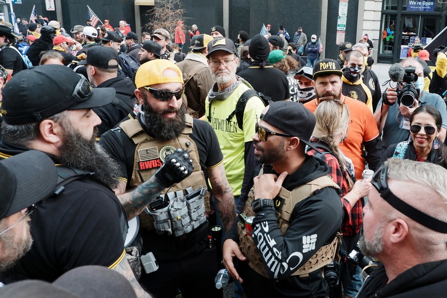 epa10608776 Enrique Tarrio (C-R), the leader of the Proud Boys far-right group, and Jeremy Bertino (C-L), a member of the Proud Boys, talk as they stand with others before marching into Freedom Plaza, ...