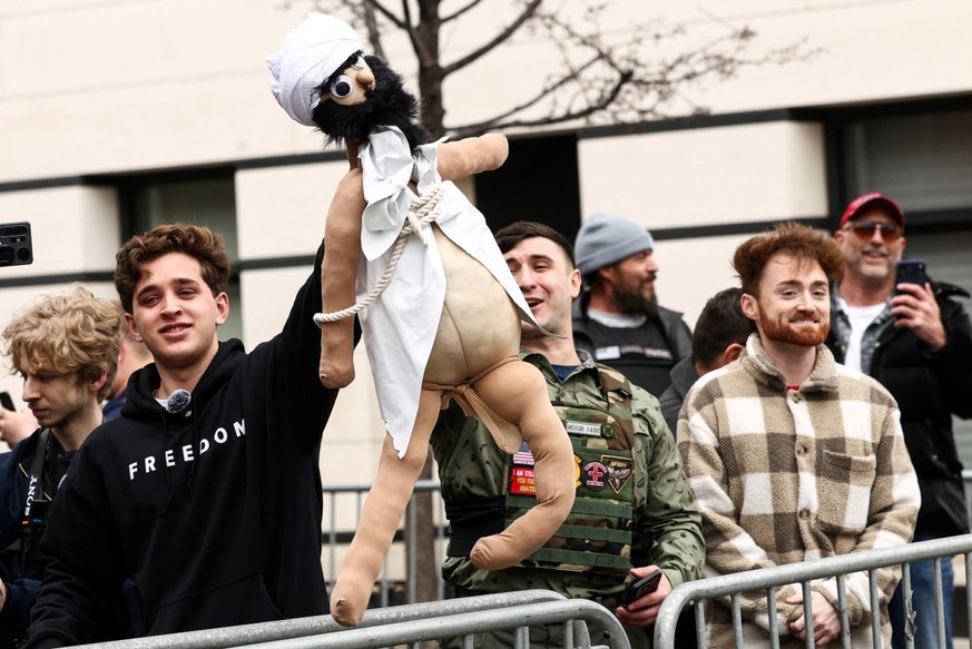 Far-right influencer Jake Lang (C) and a supporter hold a puppet representing a Muslim at a protest he organized against alleged "Islamification" and to ask for a "stop of public Muslim ...