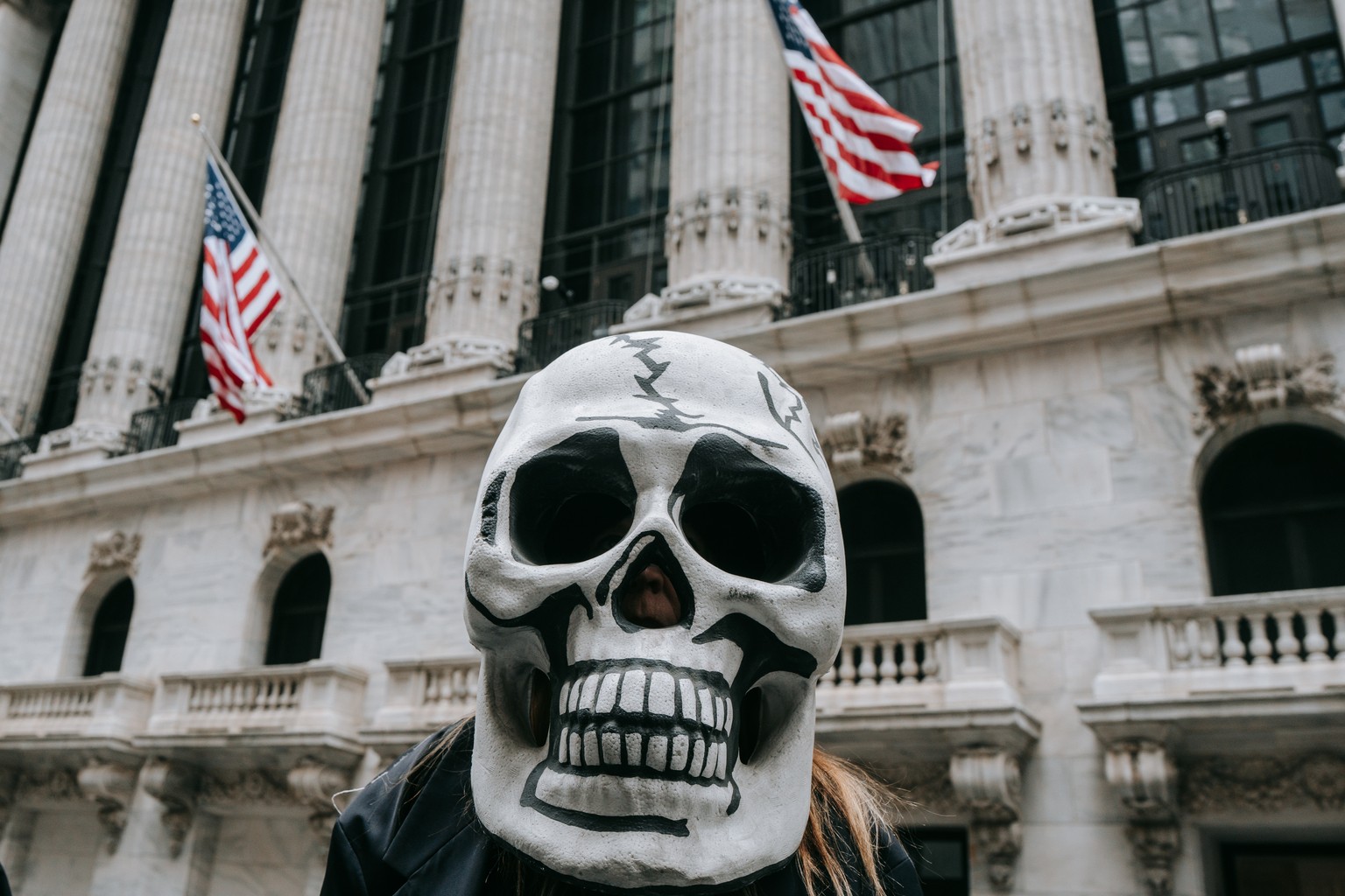 epa11966797 A protester wears a skull mask during a die-in outside of the NY Stock Exchange as thousands flood the streets in opposition to proposed budget cuts in New York City, New York, 15 March 20 ...