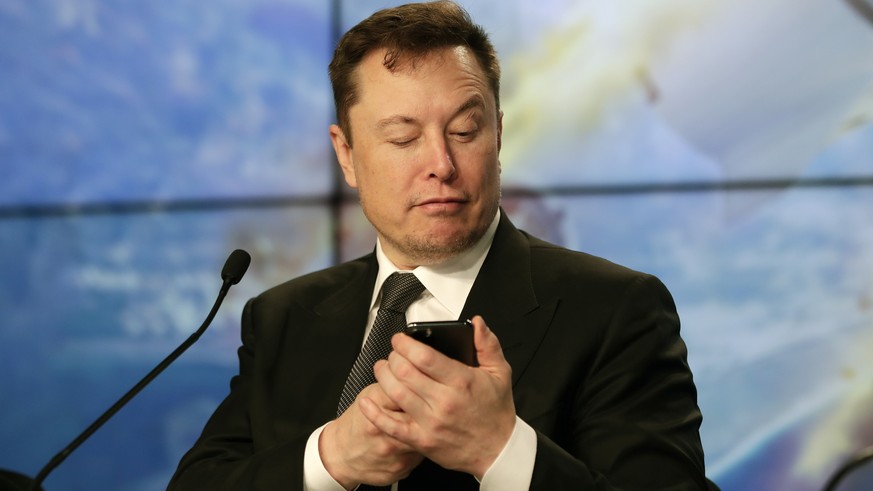 FILE - Elon Musk founder, CEO, and chief engineer/designer of SpaceX jokes with reporters as he pretends to search for an answer to a question on a cell phone during a news conference after a Falcon 9 ...