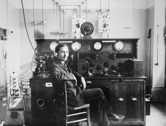 Roland Pièce, directeur technique de la première station de radio suisse « Champ-de-l'Air », assis devant les équipements de diffusion vers 1922.