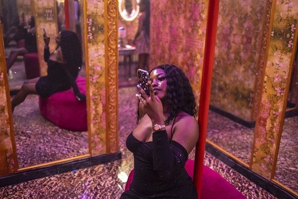 A patron uses her phone to take a photo of herself in the mirror as she sits on a sofa inside the restroom of Zaza restaurant and lounge in Lagos, on August 25, 2025. In Nigeria, bathroom selfies are  ...