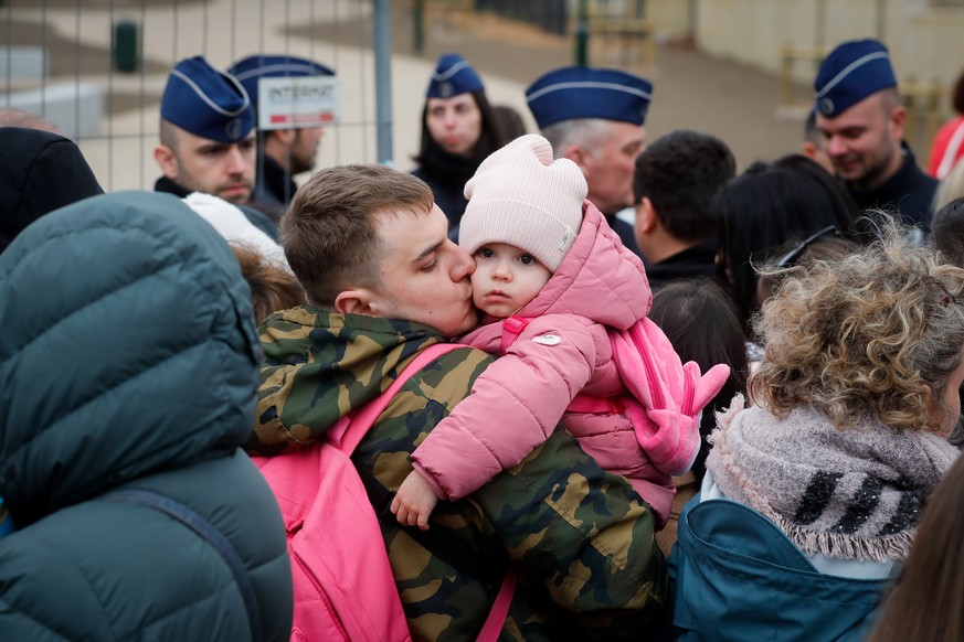 epa09824475 A father and his child who fled Ukraine to Belgium after Russia&#039;s invasion of Ukraine line up outside an immigration office in Brussels, Belgium, 14 March 2022. The first temporary re ...
