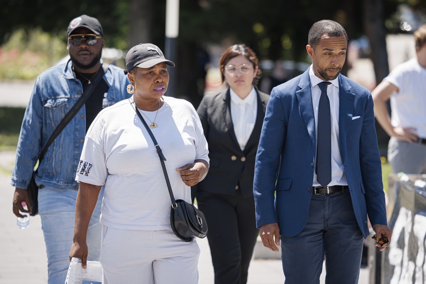 Le frere de Mike Ben Peter (gauche), la veuve de Mike Ben Peter, Bridget Efe (2e gauche) et Simon Ntah, avocat de la famille de Mike Ben Peter (driote), arrivent avant l&#039;annonce du verdict du pro ...