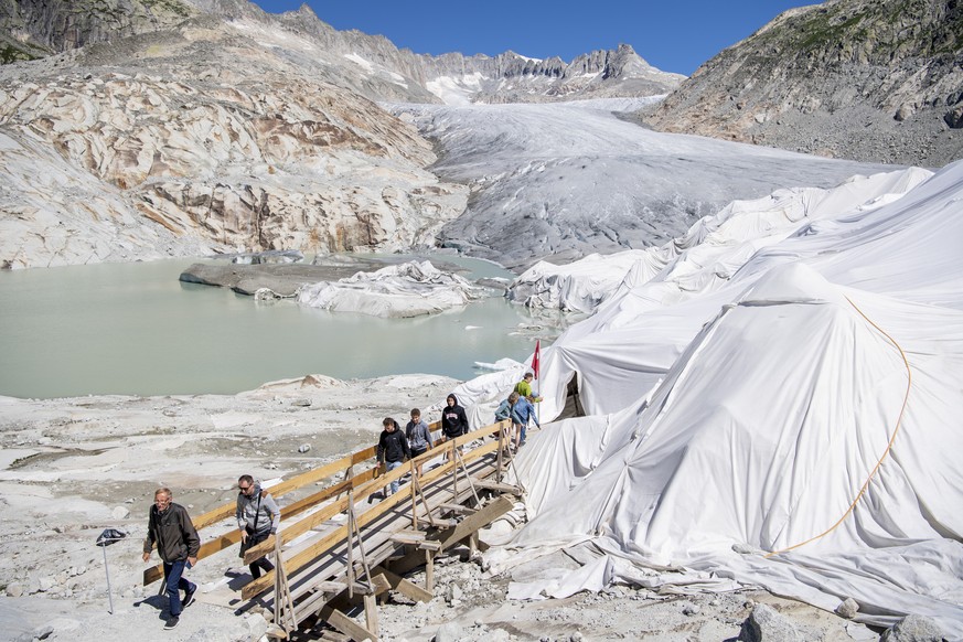 People visit the Rhone Glacier covered in blankets to protect it from the sun, above Gletsch near the Furkapass in Switzerland, Wednesday, July 13, 2022. The Alps oldest glacier is protected by specia ...