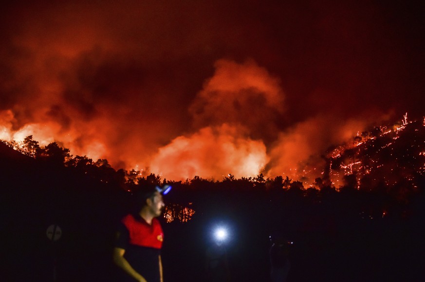 A man leaves as advancing fires rage the Hisaronu area, Turkey, Monday, Aug. 2, 2021. For the sixth straight day, Turkish firefighters battled Monday to control the blazes that are tearing through for ...