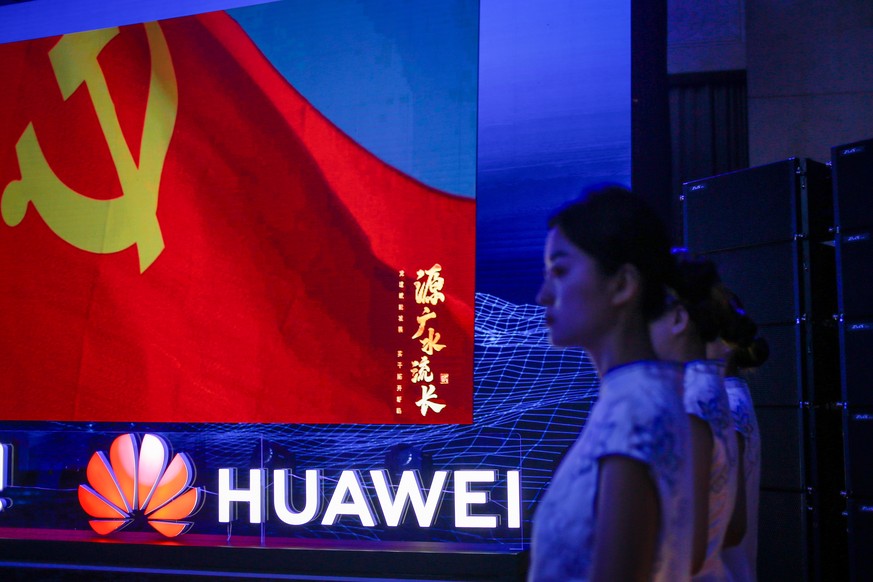 epa10752820 Women stand along the logo of Huawei during the launch event of the first commercial application of artificial intelligence for the mining industry in Jinan, Shandong province, China, 18 J ...