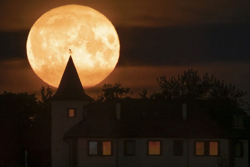The full moon rises over a private house in the village of Putilovo, 70 kilometeres (43 miles) east of St. Petersburg, Russia, late Wednesday, July 13, 2022. (AP Photo/Dmitri Lovetsky)
