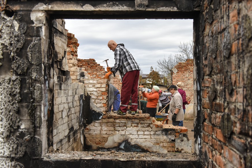 epa10273113 Volunteers clean the debris of a house, destroyed in combat action in Novoselivka village, Chernihiv region, Ukraine, 29 October 2022. A group of local people from Chernihiv and the nearby ...