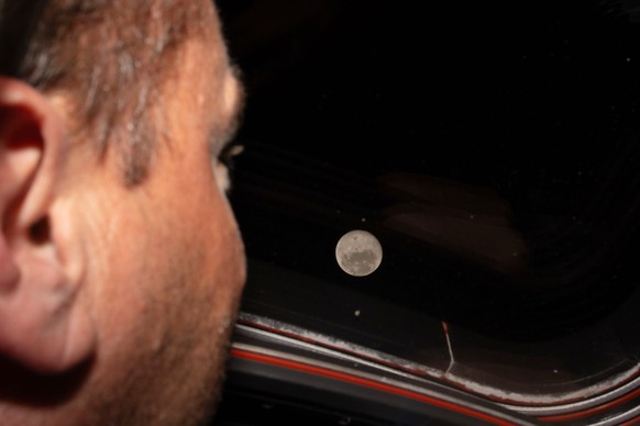 In this photo provided by NASA, Artemis II commander and NASA astronaut Reid Wiseman looks out one of the Orion spacecraft's main cabin windows at the Moon ahead of the crew's lunar flyby on ...