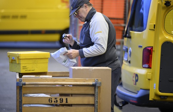 Ein Zusteller der Schweizerischen Post scannt ein Paket mit einem Handscanner waehrend dem Beladen seines Fahrzeugs mit Briefen und Paketen, fotografiert am Dienstag, 24. Februar 2026 beim Verteilzent ...