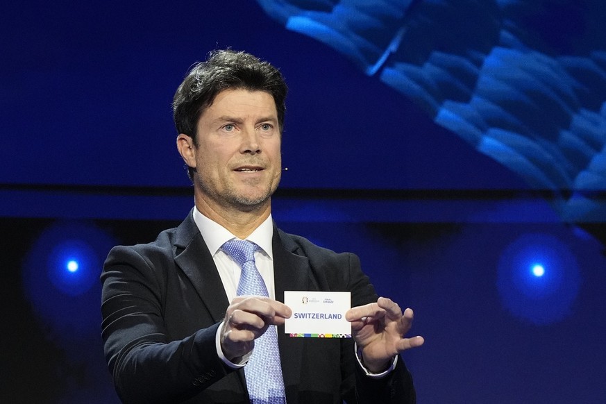 Former soccer player Brian Laudrup holds up the name Switzerland during the draw for the UEFA Euro 2024 soccer tournament finals in Hamburg, Germany, Saturday, Dec. 2, 2023. (AP Photo/Martin Meissner)