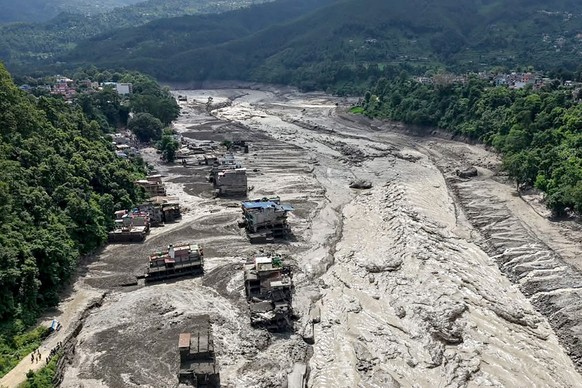 Houses lie partially submerged in muddy water along a riverside after flash floods at Trishuli Bazar in Nepal's Nuwakot district on August 26, 2026. A massive flood swept through Nepal's nor ...