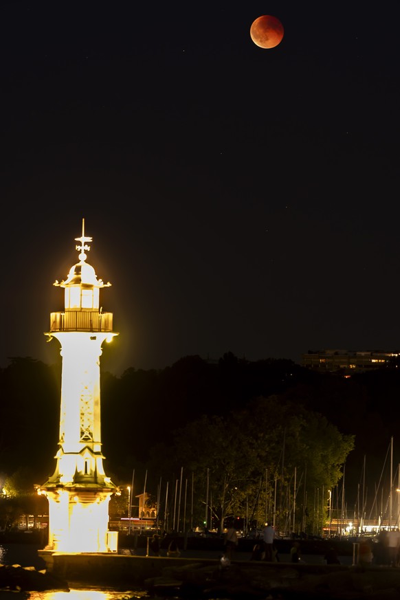 epa12360743 The Blood Moon is seen behind the lighthouse at the Bains des Paquis during a total lunar eclipse in the sky over of Geneva, Switzerland, 07 September 2025. EPA/SALVATORE DI NOLFI