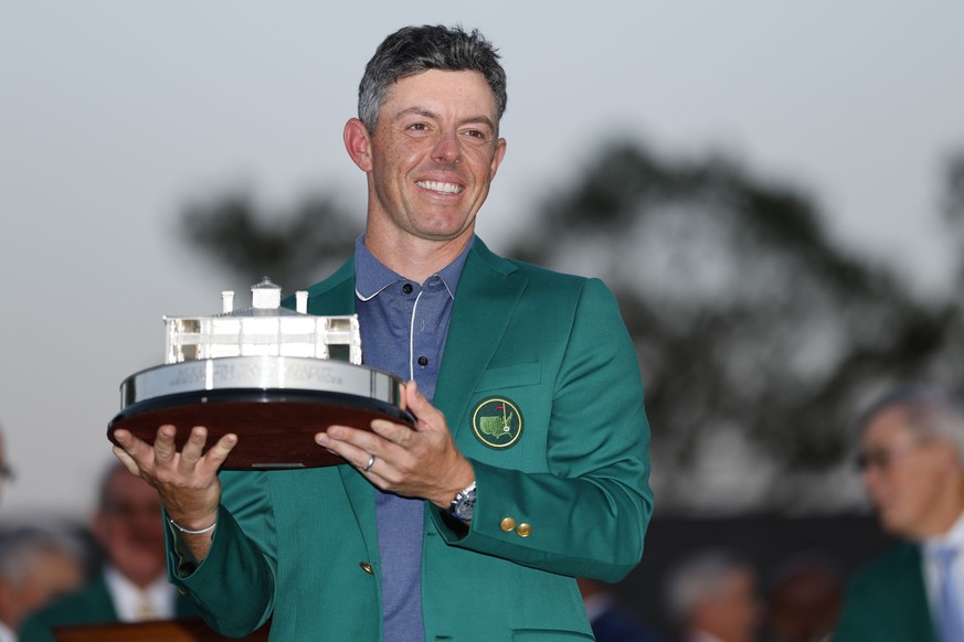 epa12030850 Rory McIlroy of Northern Ireland wearing his Masters green jacket holds up his trophy after winning the 2025 Masters Tournament at the Augusta National Golf Club in Augusta, Georgia, USA,  ...