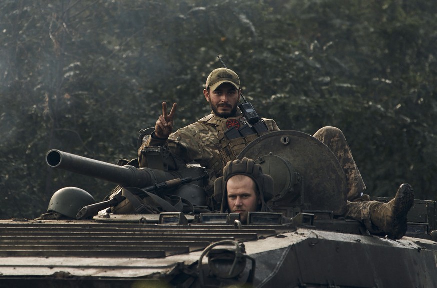 A Ukrainian soldier shows a V-sign atop a vehicle in Izium, Kharkiv region, Ukraine, Tuesday, Sept. 13, 2022. Ukrainian troops piled pressure on retreating Russian forces Tuesday, pressing deeper into ...