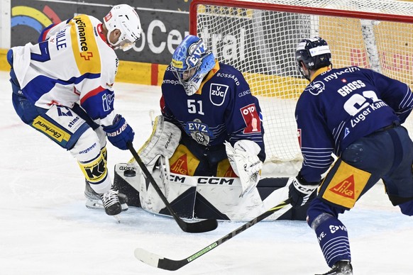 Zugs Goalie Luca Holestein, und Nico Gross, rechts, kaempfen um den Puck, gegen Klotens Eric Faille, links, im Qualifikations - Spiel der National League zwischen dem EV Zug und dem EHC Kloten am Sams ...