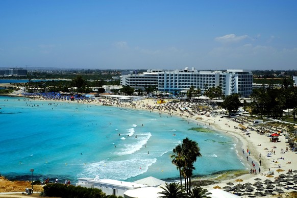 A view of the famous Nissi Beach with people as they enjoy the beach and the sea in southeast resort of Ayia Napa, in the eastern Mediterranean island of Cyprus, Saturday, May 22, 2021. Cypriot hotel  ...