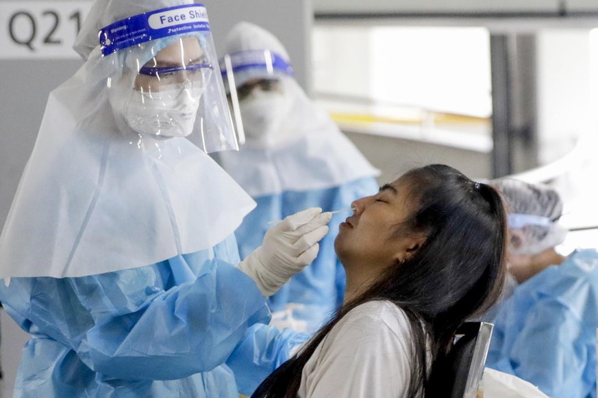 epa09440025 A shopping mall staff member (R) undergoes a COVID-19 nasal swab test during the reopening of a major shopping mall in Bangkok, Thailand, 01 September 2021. Thailand on 01 September eased  ...