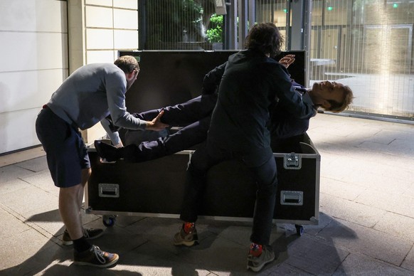 Greenpeace environmental activists open a flight case containing a wax statue of French President Emmanuel Macron, stolen from the Grevin Museum, during an action outside the EDF headquarters in Paris ...