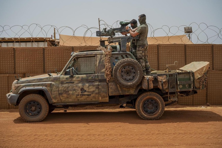French Barkhane force commandos mount a machine gun on a camouflaged pickup as Malian workers drive by before heading on a mission from their base in Gao, Mali Monday June 7, 2021. After France suspen ...