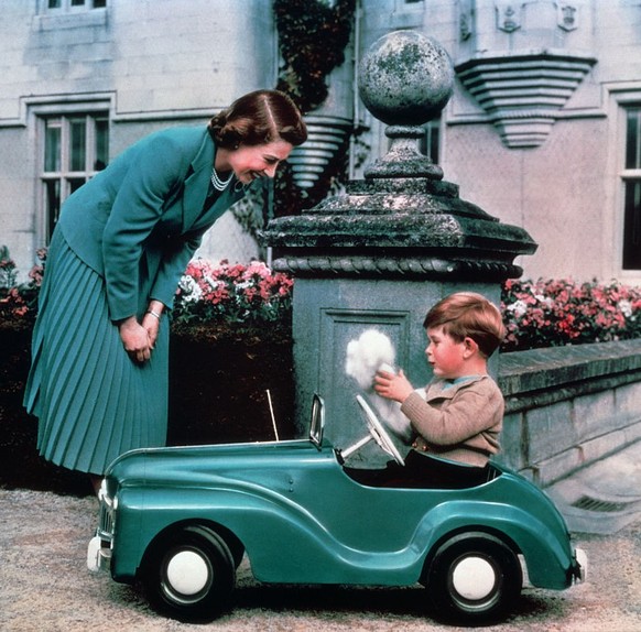 Queen Elizabeth watches her son Prince Charles driving in a toy car on the grounds of Balmoral Castle. (Photo by © Hulton-Deutsch Collection/CORBIS/Corbis via Getty Images)