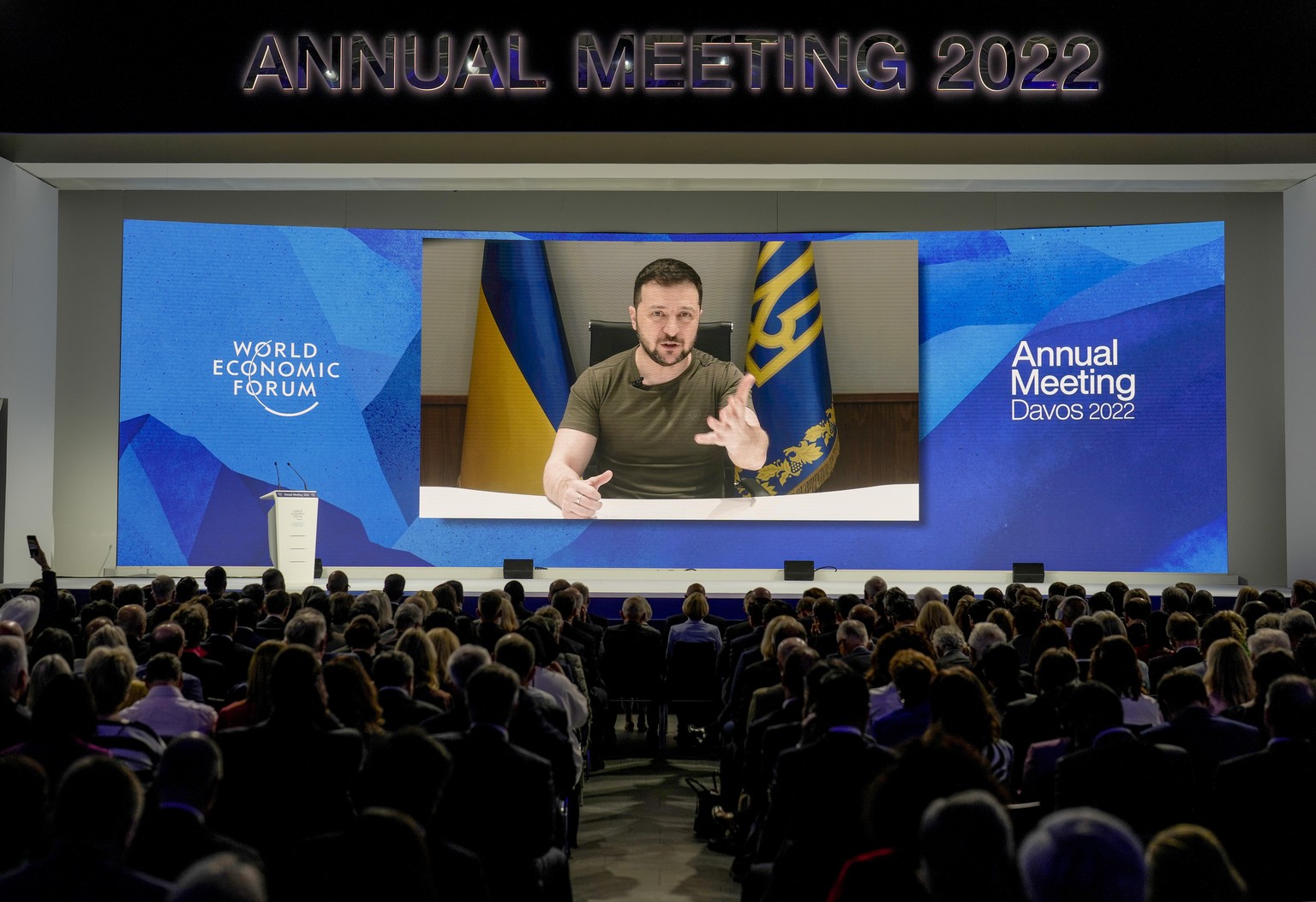 Ukrainian President Volodymyr Zelenskyy displayed on a screen as he addresses the audience from Kyiv on a screen during the World Economic Forum in Davos, Switzerland, Monday, May 23, 2022. The annual ...