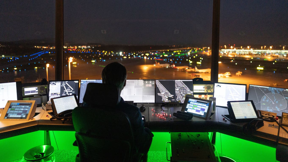 Un employé de Skyguide vérifie les moniteurs la nuit et a une vue sur l&#039;aéroport de Zurich.