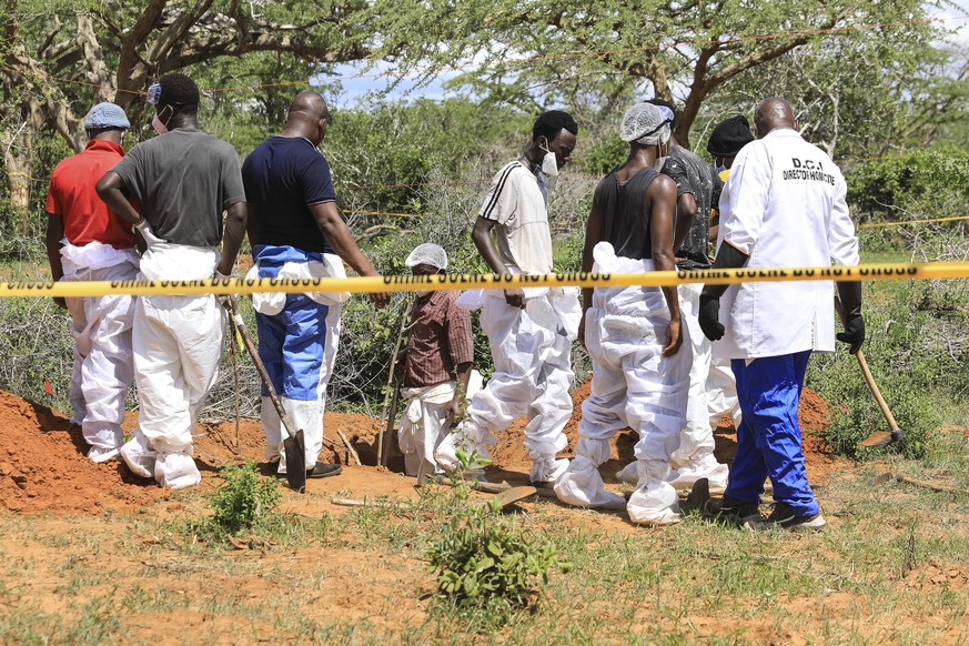 epa10588058 Kenyan homicide detectives and forensic experts from the Directorate of Criminal Investigations (DCI), examine exhumed bodies from several shallow mass graves of suspected members of a Chr ...