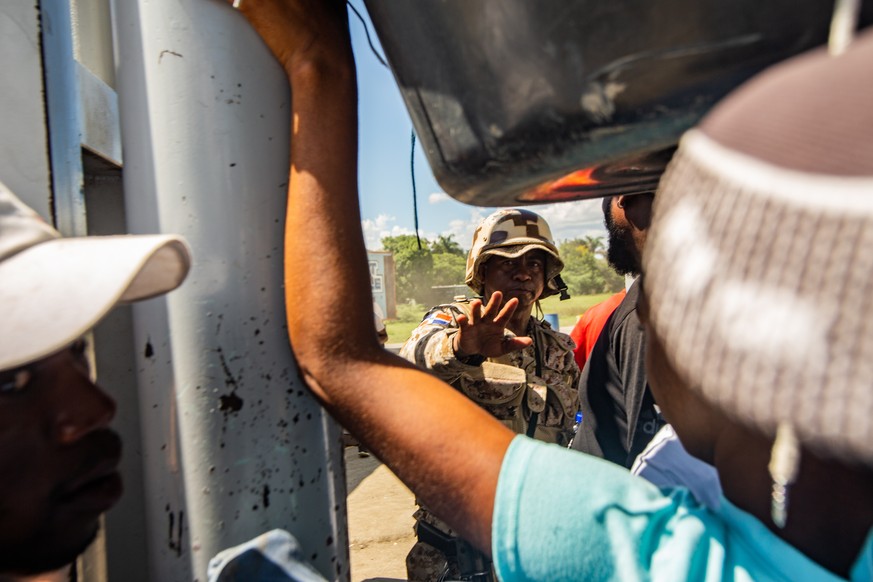 epa11599272 A member of the Dominican Republic army guards the border, as seen from Belladere, Haiti, 11 September 2024. The border between Haiti and the Dominican Republic is a busy crossing point fo ...