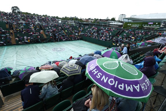 epa10727626 Spectators sit under umbrellas during rain at the Wimbledon Championships, Wimbledon, Britain, 05 July 2023. EPA/ADAM VAUGHAN EDITORIAL USE ONLY