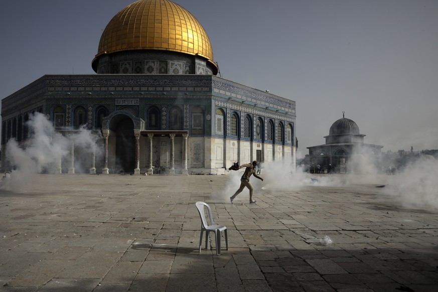 Palestinian man run away from tear gas during clashes with Israeli security forces in front of the Dome of the Rock Mosque at the Al Aqsa Mosque compound in Jerusalem&#039;s Old City Monday, May 10, 2 ...