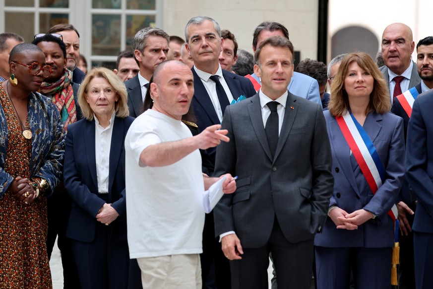 epa12893264 France's President Emmanuel Macron (R) listens to French raper Virus, next to French Culture Minister Catherine Pegard (2L) and French radio host Aline Afanoukoe (L) upon his arrival  ...