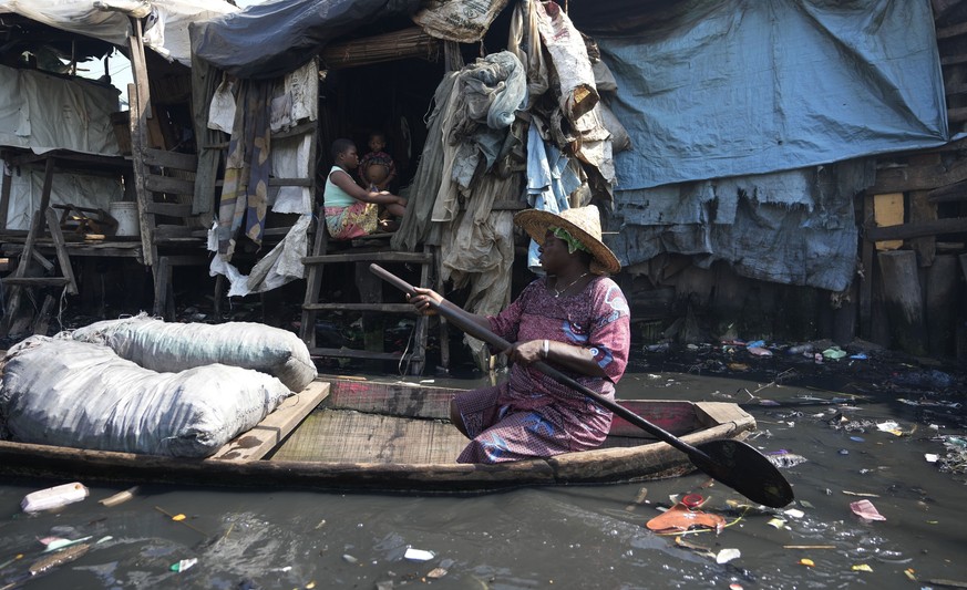 A woman paddles through water surrounded by garbage in a floating slum of Makoko, in Lagos, Nigeria, March 20, 2023. (AP Photo/Sunday Alamba)