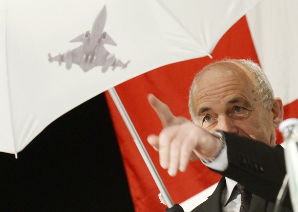 Bundesrat Ueli Maurer spannt einen Regenschirm mit dem Symbol eines Gripen Kampfjets anlaesslich der Delegiertenversammlung der SVP am Samstag, 5. April 2014, in Naefels. (KEYSTONE/Steffen Schmidt)