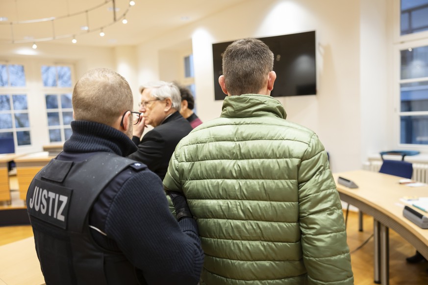L'accusé, à droite, est conduit par un officier de justice, à gauche, dans la salle d'audience du tribunal de Waldshut, en Allemagne.