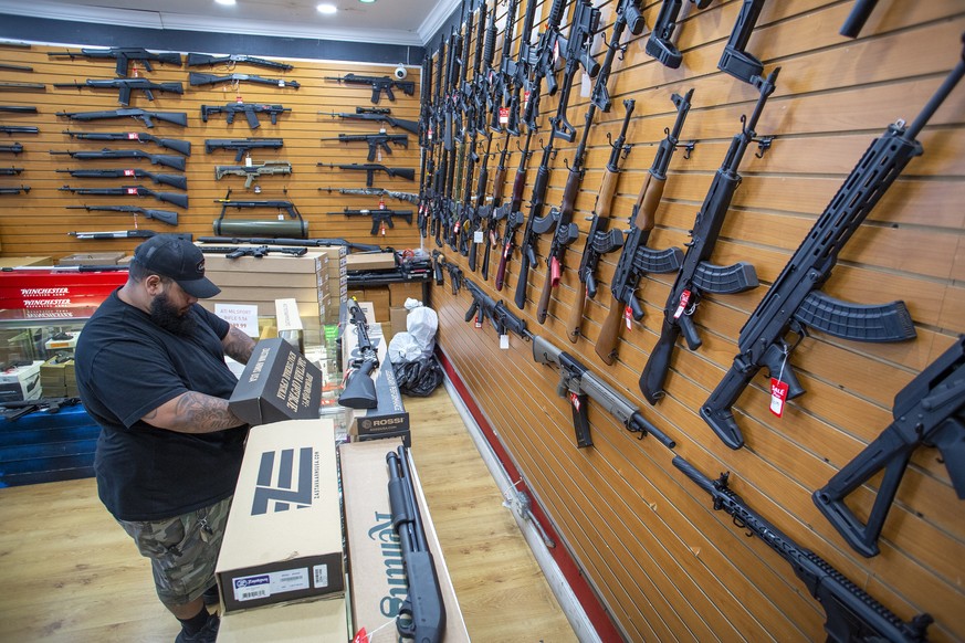epa10028663 A worker at the Miami Guns Store and Range checks a semi-automatic gun, in Hialeah, Florida, USA, 22 June 2022. On 21 June a bipartisan group of US senators released the Bipartisan Safer C ...