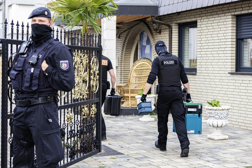 A police officer stands in front of a villa in Leverkusen, Germany, Tuesday, June 8, 2021. Special police units searched around 30 buildings in connection with money laundering and organized crime in  ...