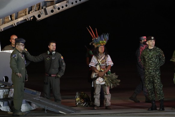 Military personnel and Indigenous leaders stand under a plane after the arrival of four Indigenous brothers who were missing after a deadly plane crash at the military air base in Bogota, Colombia, Sa ...