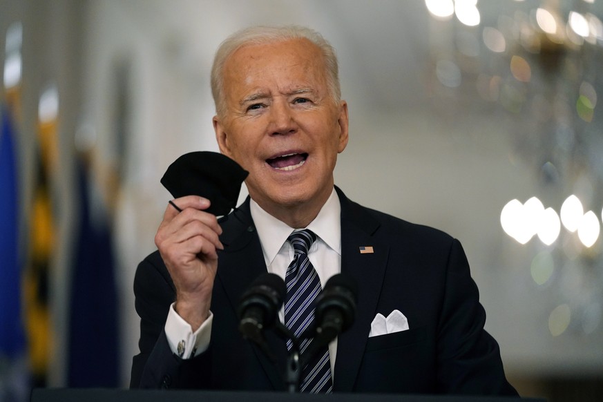 President Joe Biden holds up his face mask as he speaks about the COVID-19 pandemic during a prime-time address from the East Room of the White House, Thursday, March 11, 2021, in Washington. (AP Phot ...