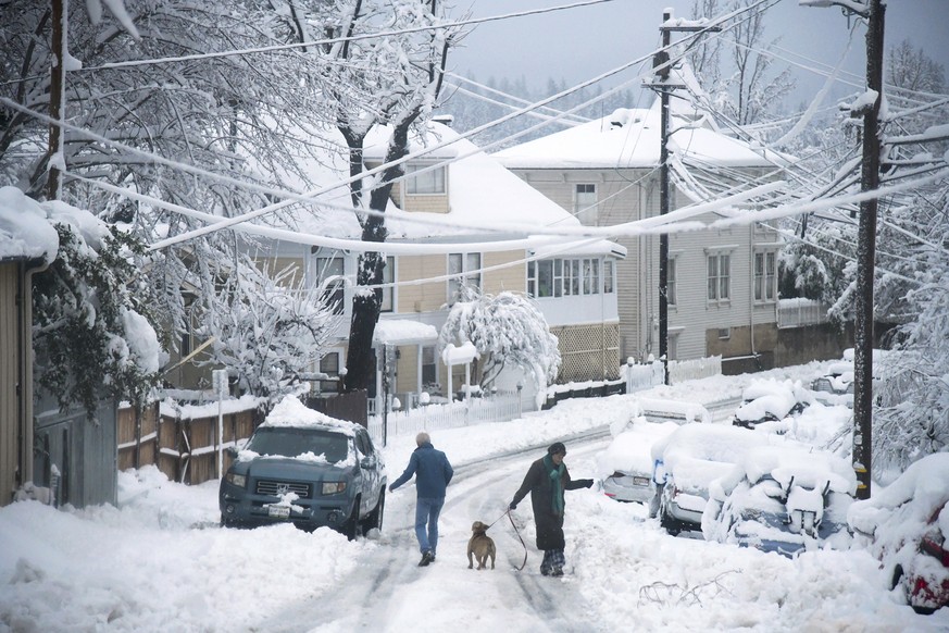 Residents navigate Broad Street in the snow in Nevada County, Calif., Monday, Dec. 27, 2021. (Elias Funez/The Union via AP)