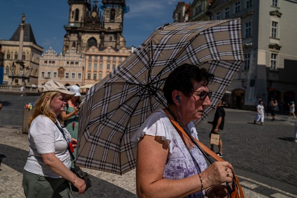 epa13069060 A woman walks with an umbrella to shield herself from the heat during a hot, sunny day at Old Town Square in Prague, Czech Republic, 27 June 2026. According to meteorologists, temperatures ...