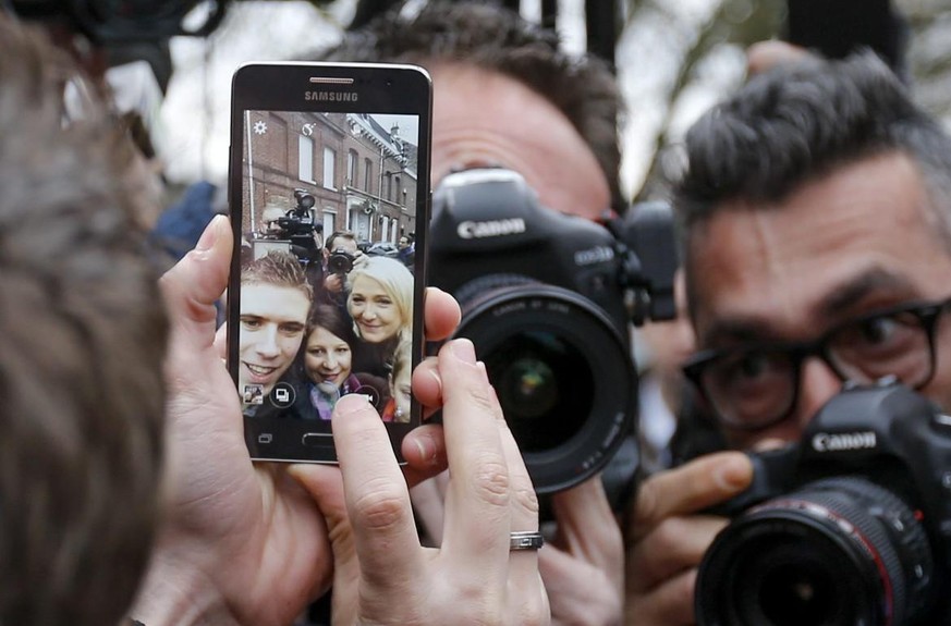 epa05067242 French far-right political party National Front (FN) Marine Le Pen pose for Selfie as photographer fights for pictures after she casts her vote at a polling station during the second round ...