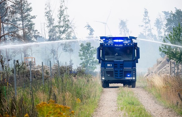 ZEITHAIN, GERMANY - JULY 3: A police water cannon is used to battle a wildfire in a forest at Gohrischheide on July 3, 2025 near Zeithain, Germany. Record-breaking high temperatures accelerated the sp ...