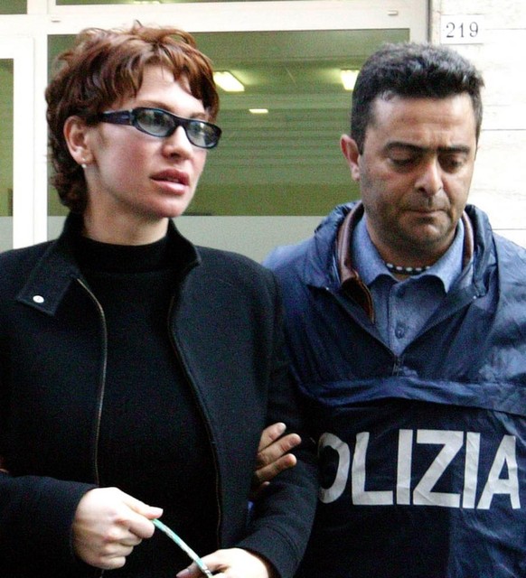 A policeman escorts Elena Korovina (L, nationality unknown ) one of the four people arrested May 14,2004 in Rimini (centre of Italy) on suspicion of supplying the cocaine on which Italian cycling cham ...