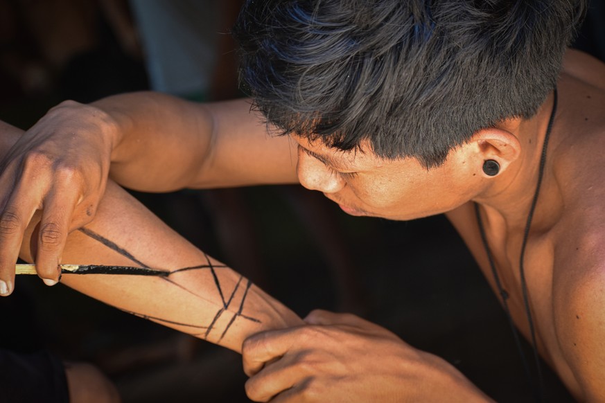 epa09170189 A Matis indigenous man decorates the arm of another tribe member as they travel to receive the vaccine against covid-19 in Atalaia do Norte, Brazil, 22 April 2021 (issued 30 April 2021). F ...