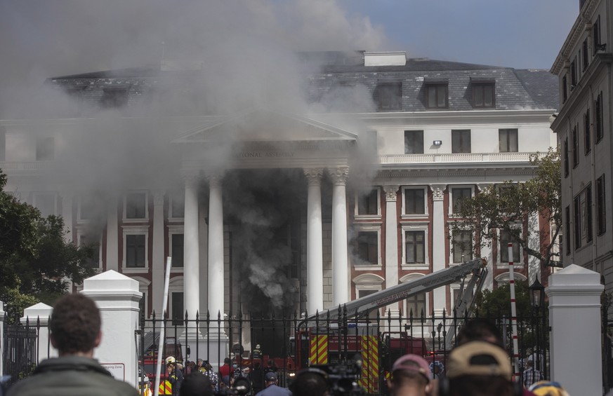 epa09663384 Smoke billows from the front of the National Assembly building in the South African Parliamentary complex in Cape Town, South Africa, 02 January 2022. Firefighters battled for hours a majo ...